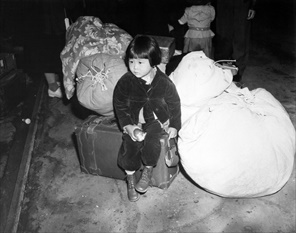 Executive Order 9066: Young Japanese American evacuee and baggage, Spring 1942